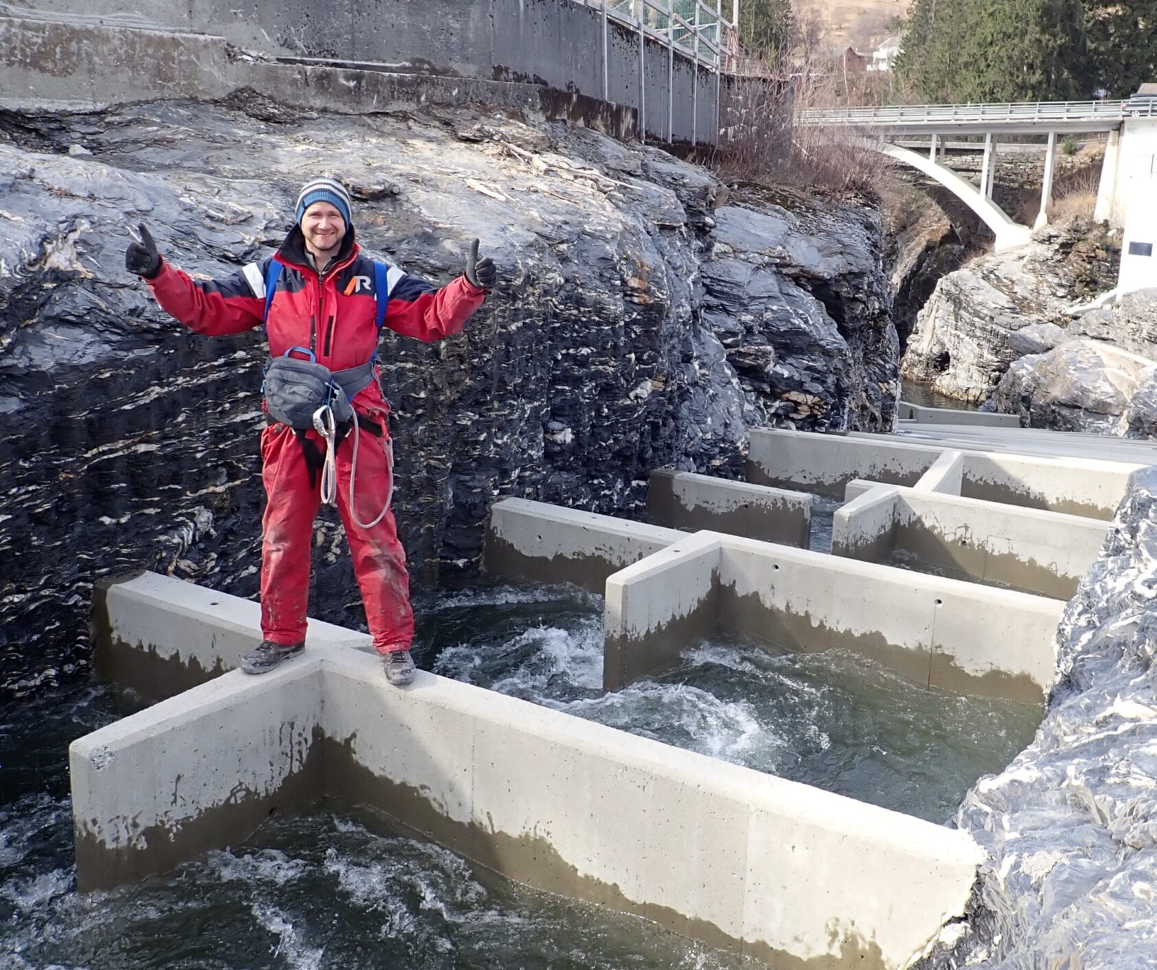 NORCE LFI, Ulrich Pulg, forsker NORCE under arbeid i Palmafossen. Arbeid som nå har gitt heder og ære., Ulrich Pulg i Palmafossen, <p>NORCE LFI</p>, Mann i kjeledress, står på betongklosser ute i fossen. Klossene  bygges for å sikre laksen som skal gå gjennom  Palmafossen.