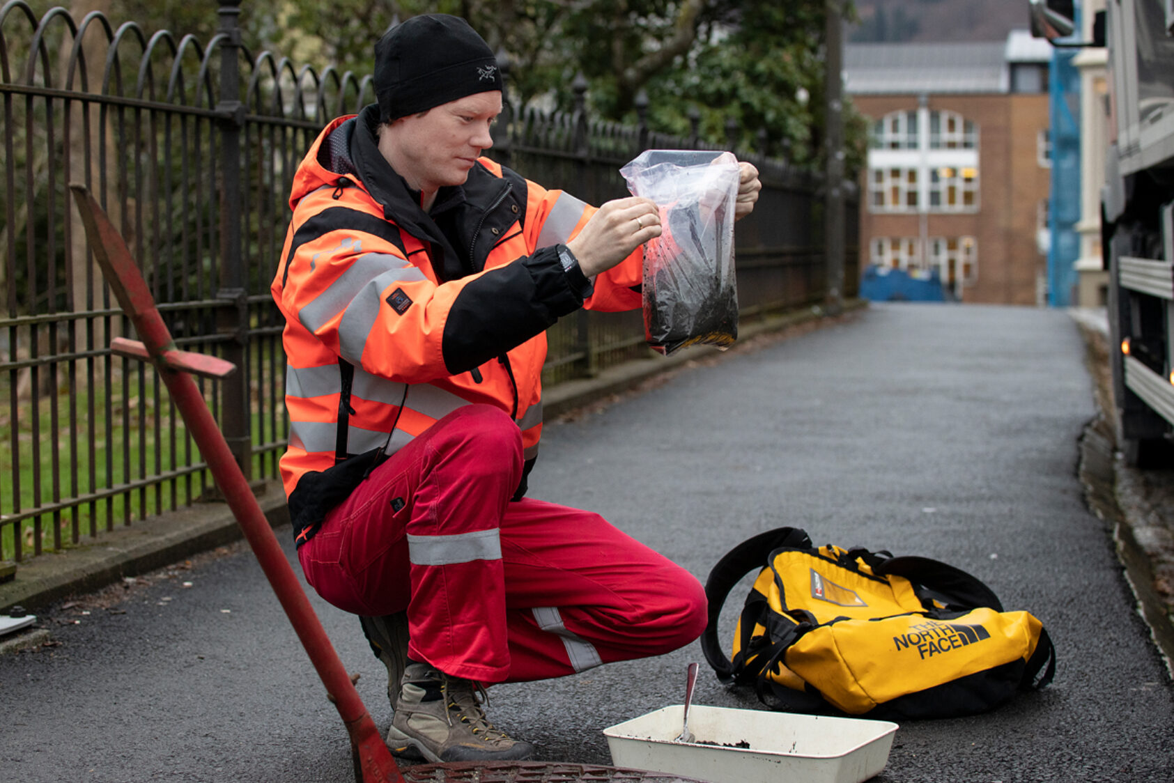 Andreas R. Graven, Her tar Einar Bye-Ingebrigtsen i NORCE prøver fra sandfang i en kum på Nygårdshøyden i Bergen., Ingebrigtsen mikroplast 1, <p>Andreas R. Graven, NORCE</p>, Mann på huk - holder gjennomsiktig plastpose med lort