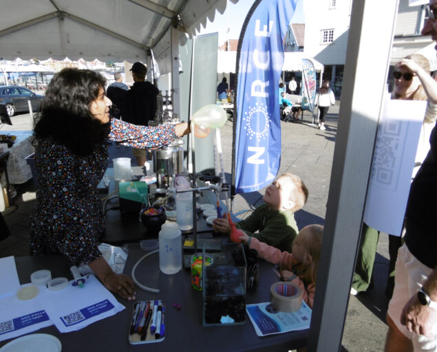 Åshild Finnestad, Ivrige barn hjelper forskeren å «produsere en mikroorganisme-ballong».  Like viktig som å bruke lab-utstyr for å få luft i ballongen var det å få lov å tegne på ballongen. Barna fikk med seg den ballongen de hadde laget., Forsk Torget Stvgr 2 foto Å F, , 
