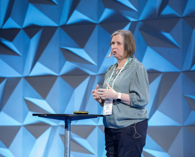 Thomas Hovmøller Ris, Restråstoff, fôrråvarer, slam og plast. Det ligger store muligheter for sirkulærøkonomi i sjømatnæringen, sa Myhr., Anne Ingeborg Myhr2, <p>Thomas Hovmøller Ris, NORCE</p>, Kvinne snakker fra en scene bak et rundt lite bord.