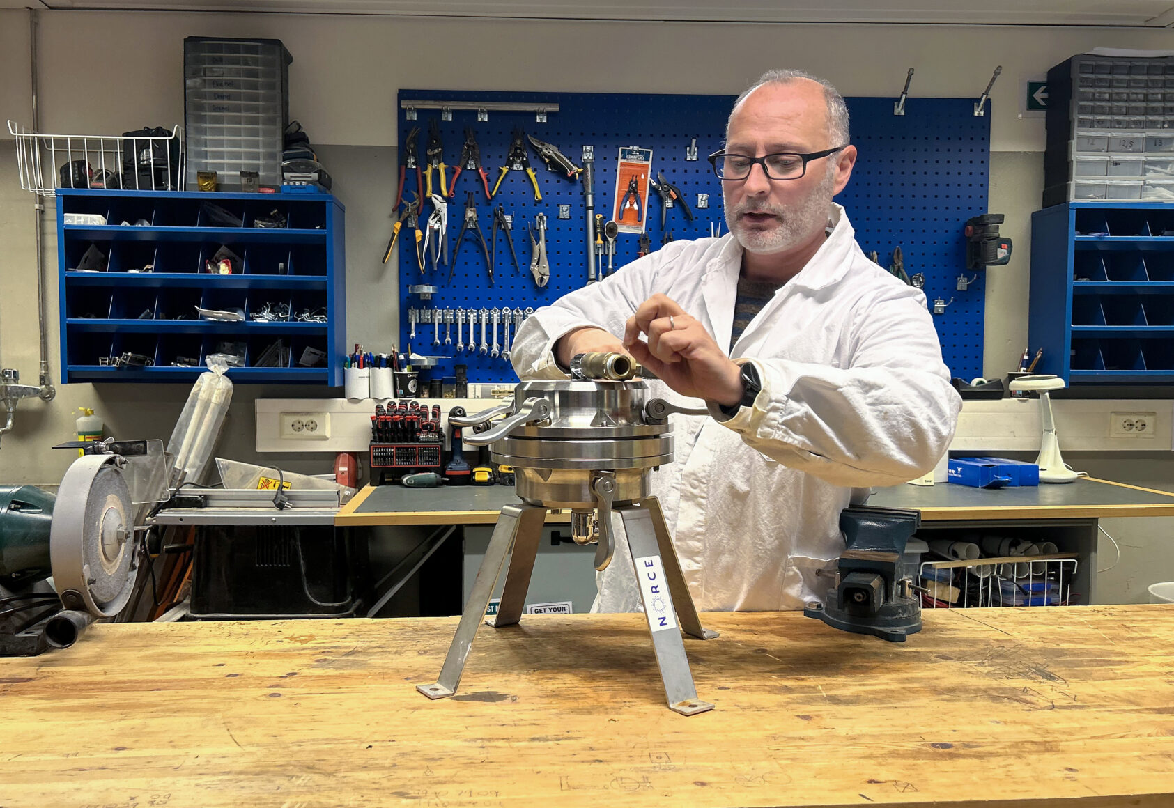 (Foto: NORCE), Seniorforsker Alessio Gomiero i NORCE med instrumentet som har stått om bord på Statsraad Lehmkuhl, og filtrert mikroplast fra havvann., Alessio gomiero mikroplast instrument, , Forsker står i verksted og ser på et instrument som kan samle mikroplast fra vann i havet.