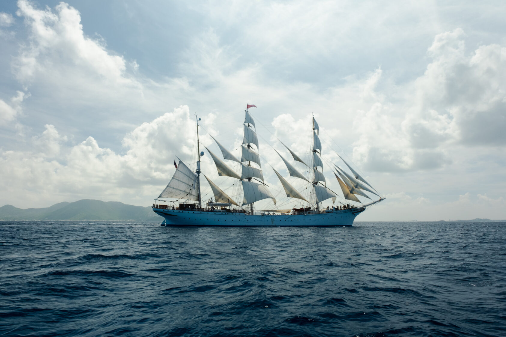 (Foto: Isak Okkenhaug/Statsraad Lehmkuhl), Statsraad Lehmkuhl i Det karibiske hav. Full seilføring gjennom Anguilla-kanalen, som skiller øyene Anguilla og Saint Martin., B Statsraad Lehmkuhl Karibiske hav OOE, , Seilskipet Statsraad Lehmkuhl for fulle seil i det karibiske hav, med lette hvite skyer og stedvis blå himmel.