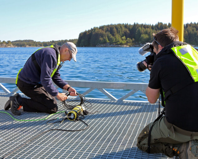 Ingvar Henne, , 4, <p>Ingvar Henne</p>, Fotograf på kne foran en mann på kne foran teknisk utstyr.